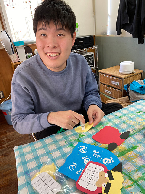 折り紙に糊を塗る、笑顔の男性